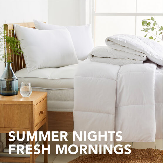 A freshly made bed with focus on the neatly folded duvets